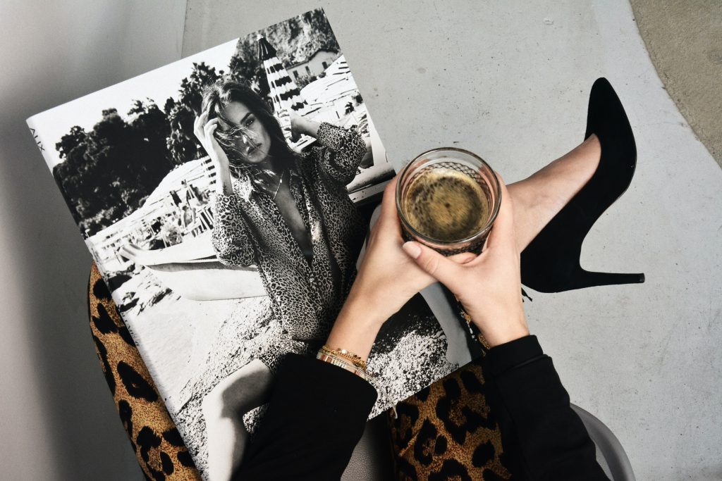 Businesswoman enjoying coffee while reading about fashion – tailored confidence with Alex Laine.